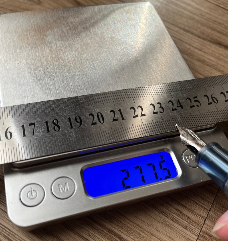 Eine XV Flex Pro Feder wird auf einer digitalen Küchenwaage gegen ein Lineal gedrückt, Anzeige 277,5 Gramm
